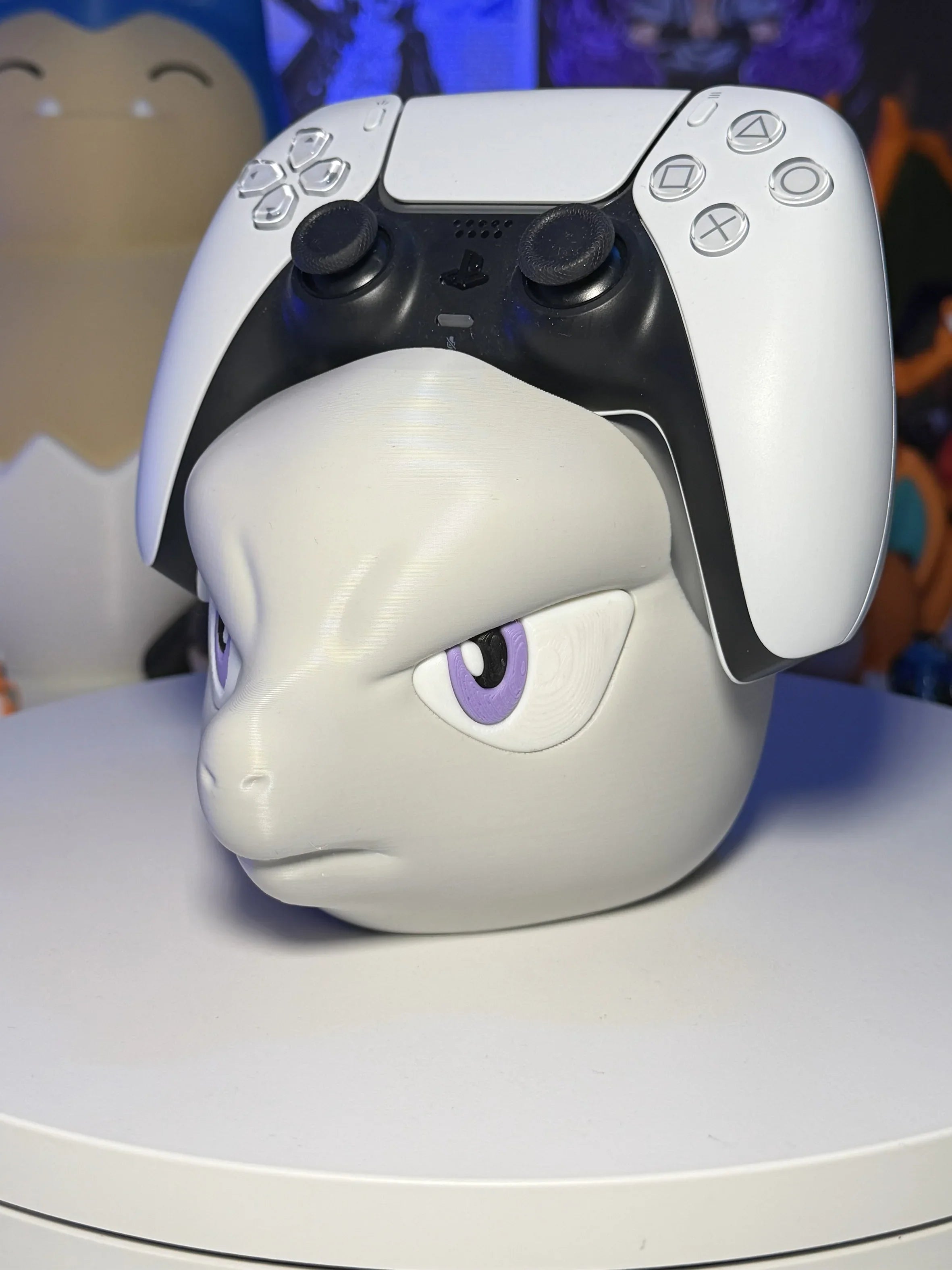 Supporto controller a forma di testa di personaggio anime grigio con occhi viola, su tavolo bianco