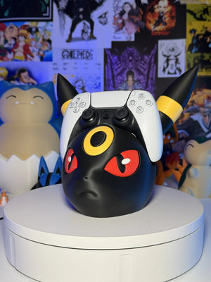 Supporto controller PlayStation a forma di Umbreon Pokémon, sfondo con poster anime.