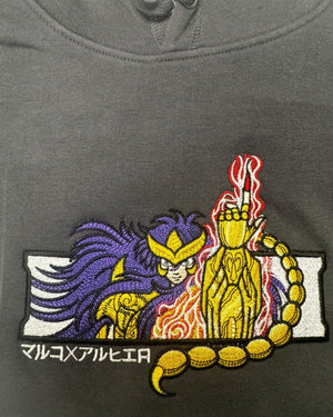 Felpa nera con ricamo anime, personaggio dorato ispirato a Saint Seiya e simbolo scorpione.