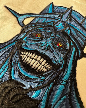 Ricamo dettagliato su felpa di personaggio oscuro in stile anime, occhi rossi e sorriso minaccioso.