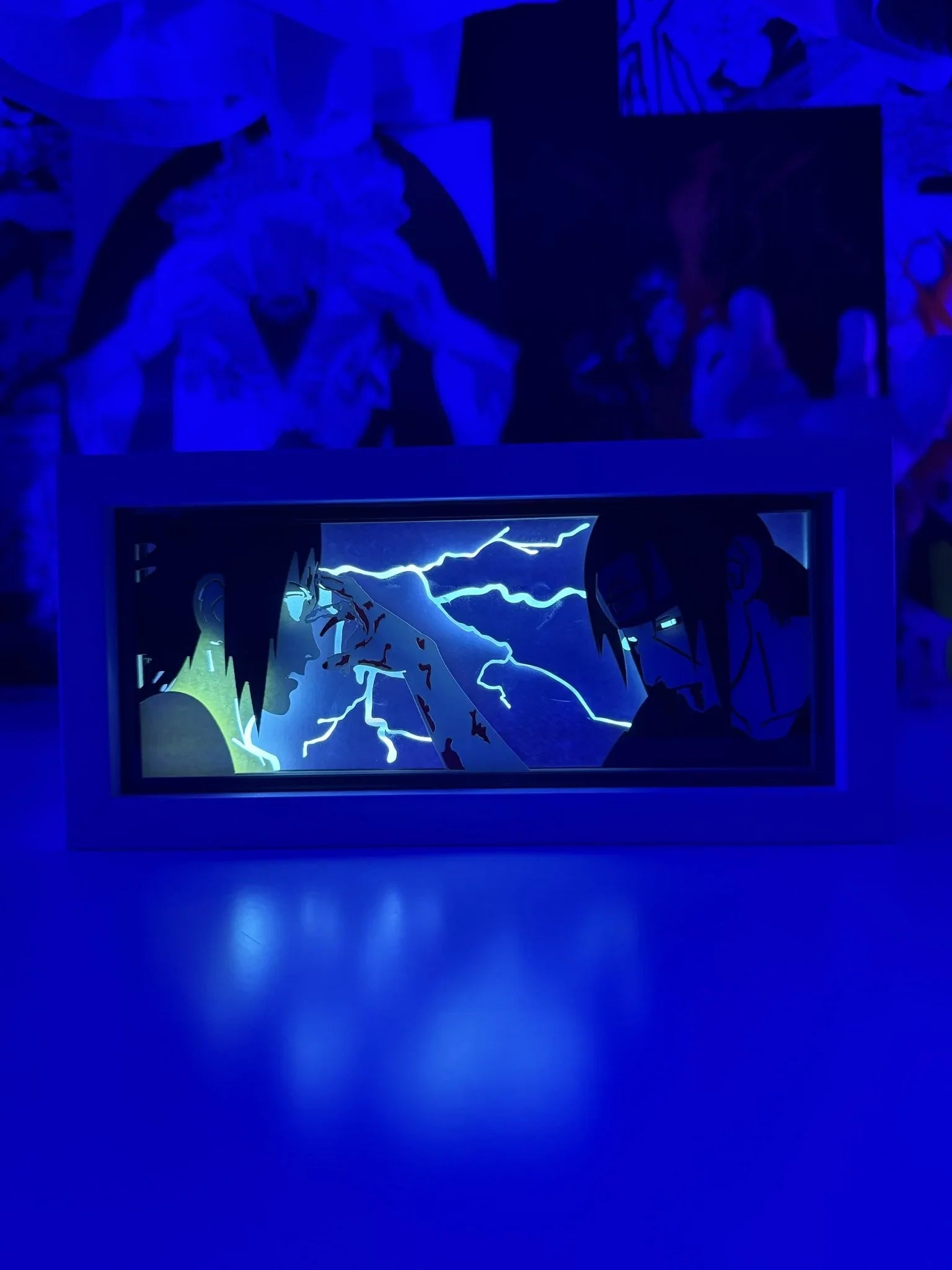 Light box LED con Itachi e Sasuke di Naruto, illuminata, con sfondo blu e fulmini.