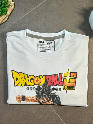 Maglietta bianca Dragon Ball Super con stampa Goku e logo colorato, formato piegato.