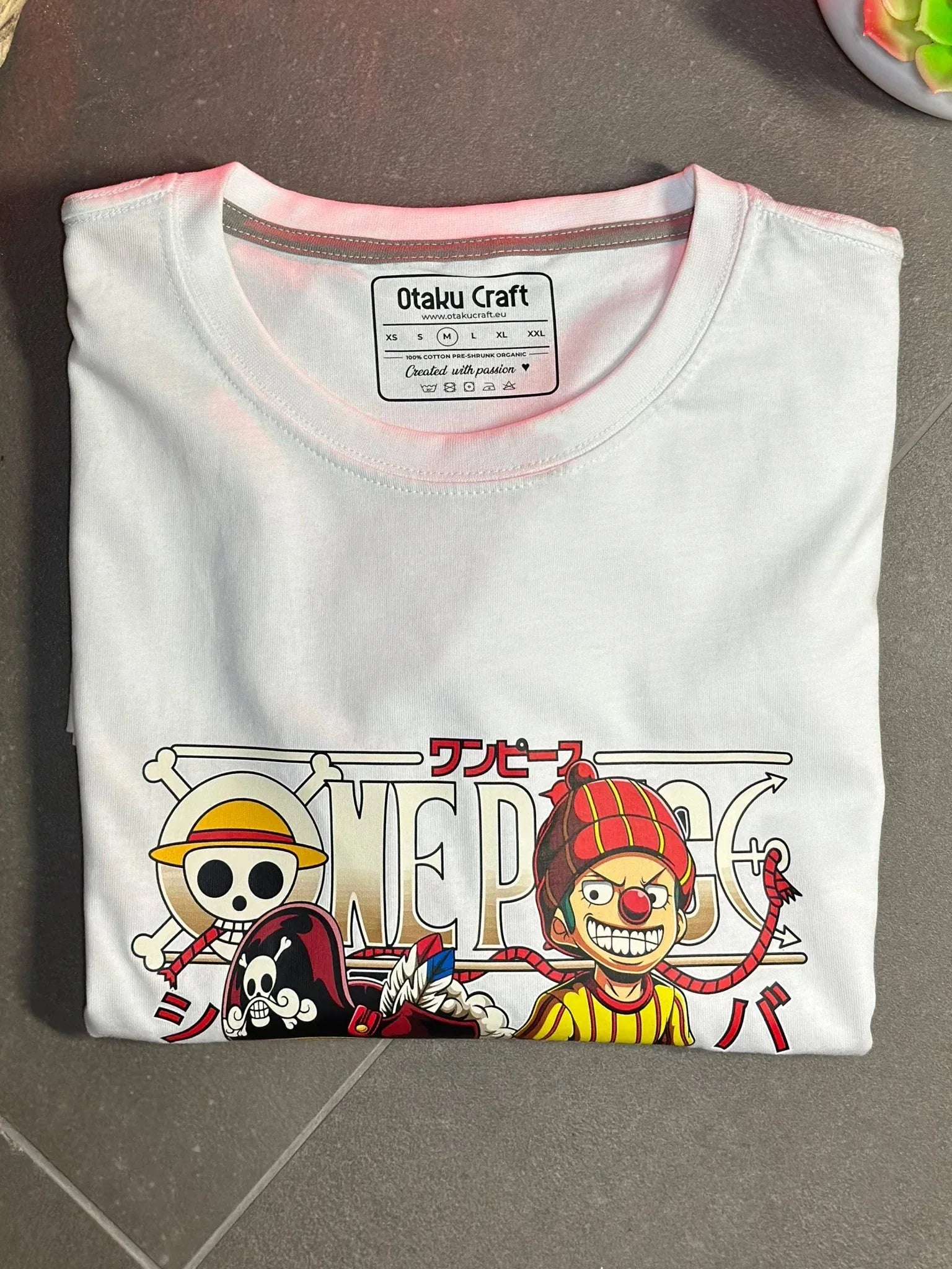 Maglietta bianca One Piece con grafica manga di Shanks e Buggy, colori vivaci ed elementi anime.