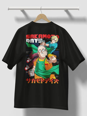 Maglietta nera con stampa anime Sakamoto Days, due personaggi e scritte giapponesi colorate.