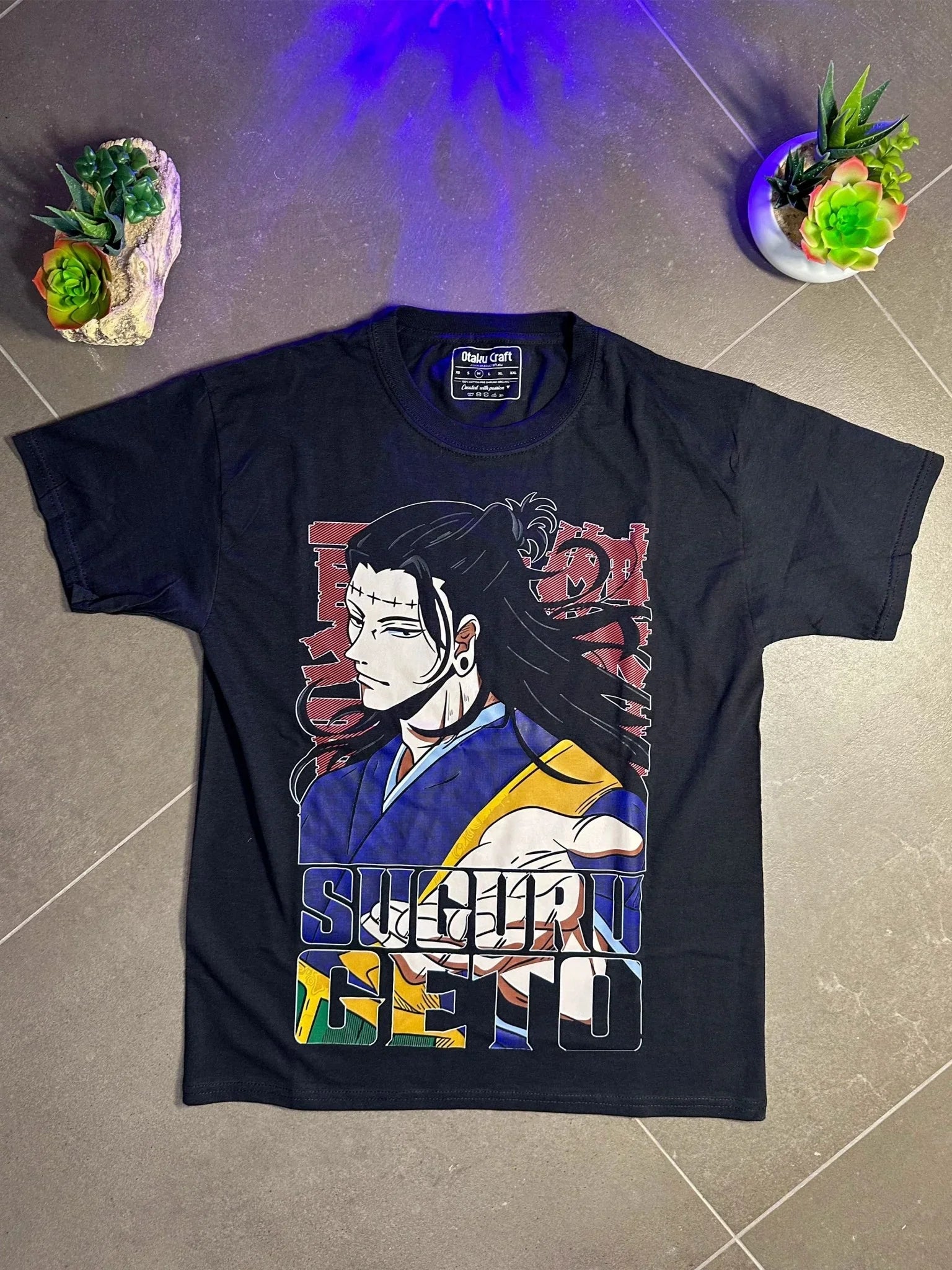 Maglietta nera Suguru Geto Jujutsu Kaisen con stampa anime, sfondo grigio e piante.