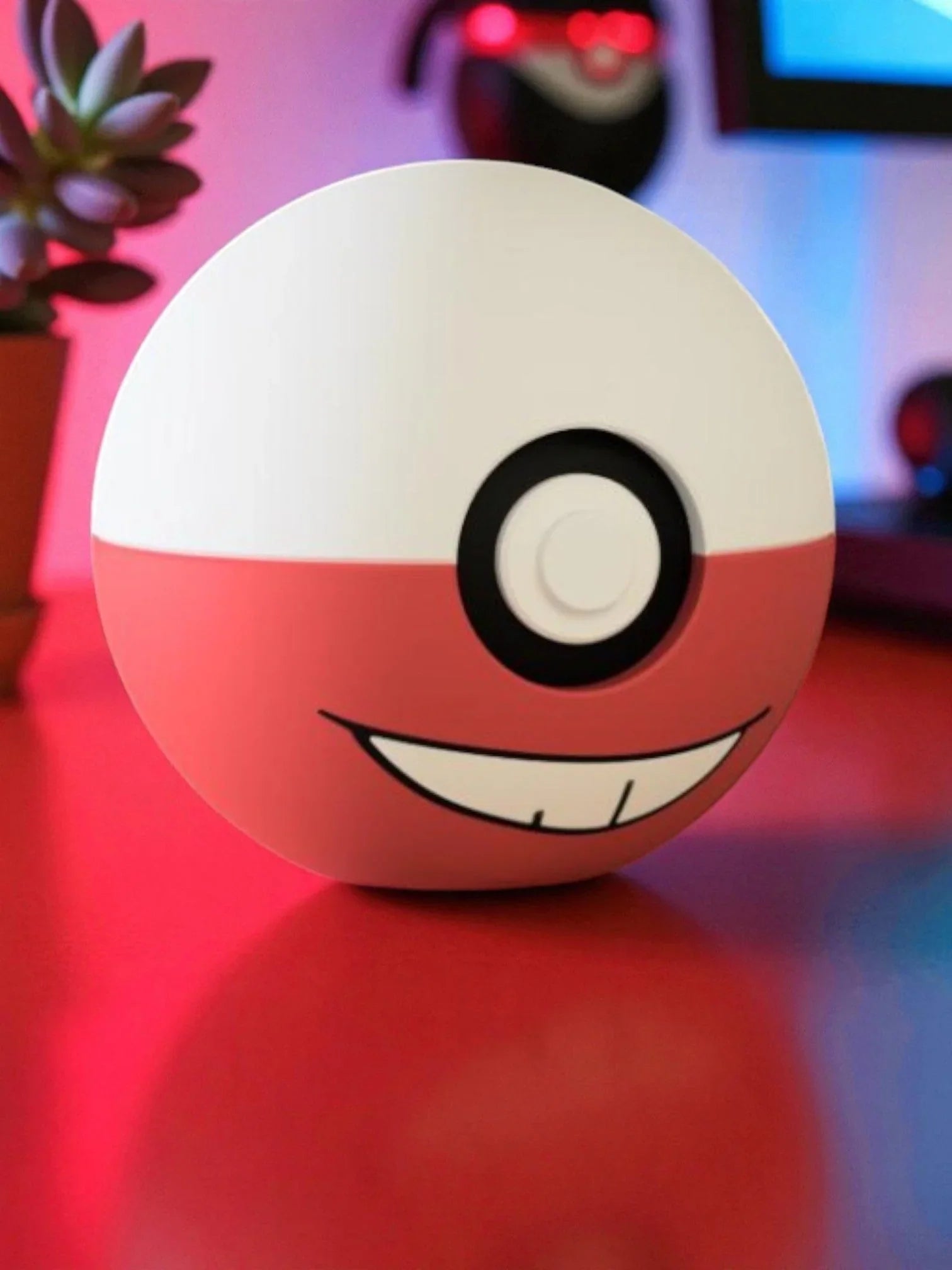 Pokeball a tema Electrode con sorriso, su scrivania rossa, illuminazione colorata