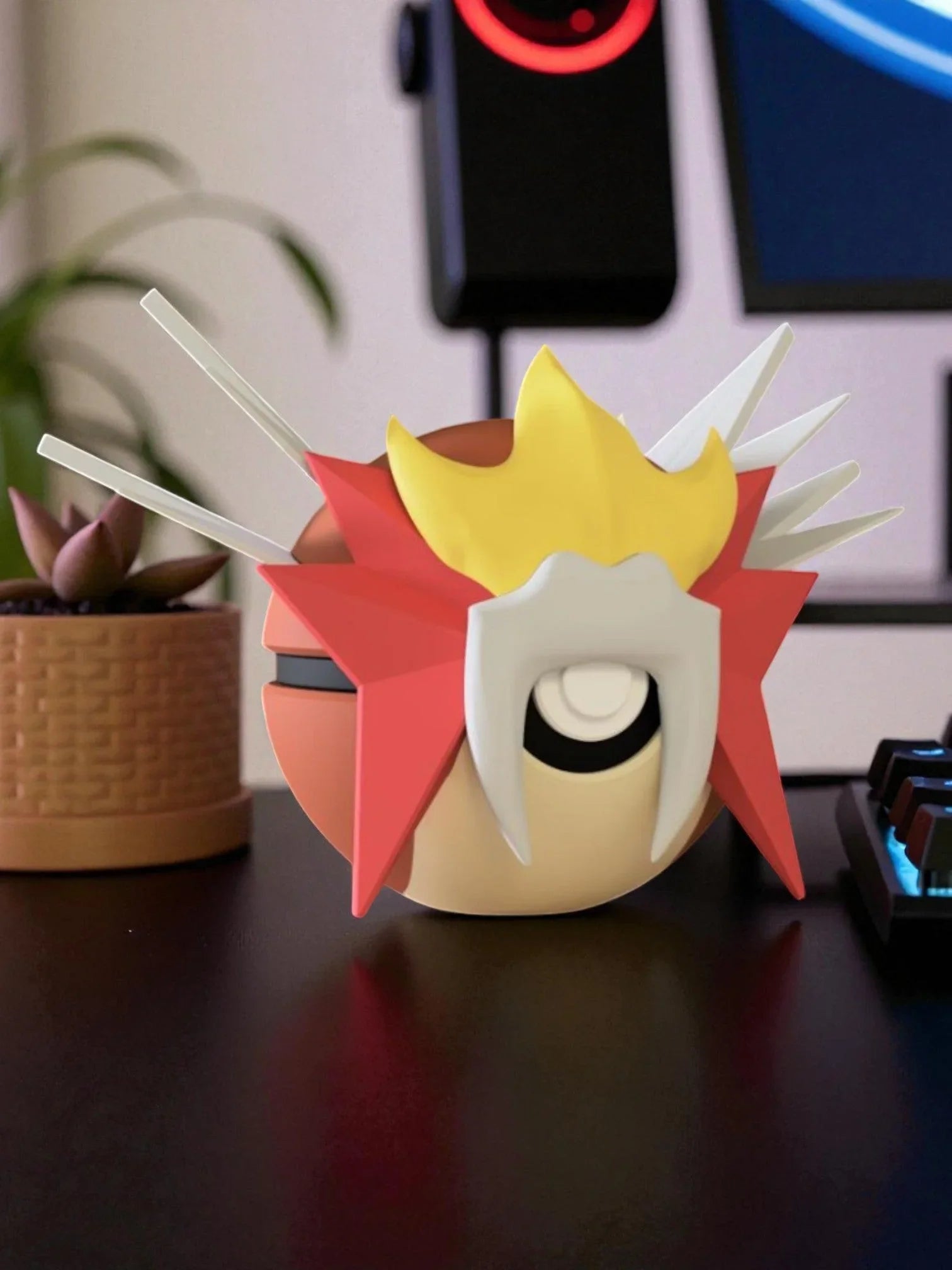 Pokeball personalizzata ispirata a Entei, decorativa, su scrivania moderna con tastiera e pianta.