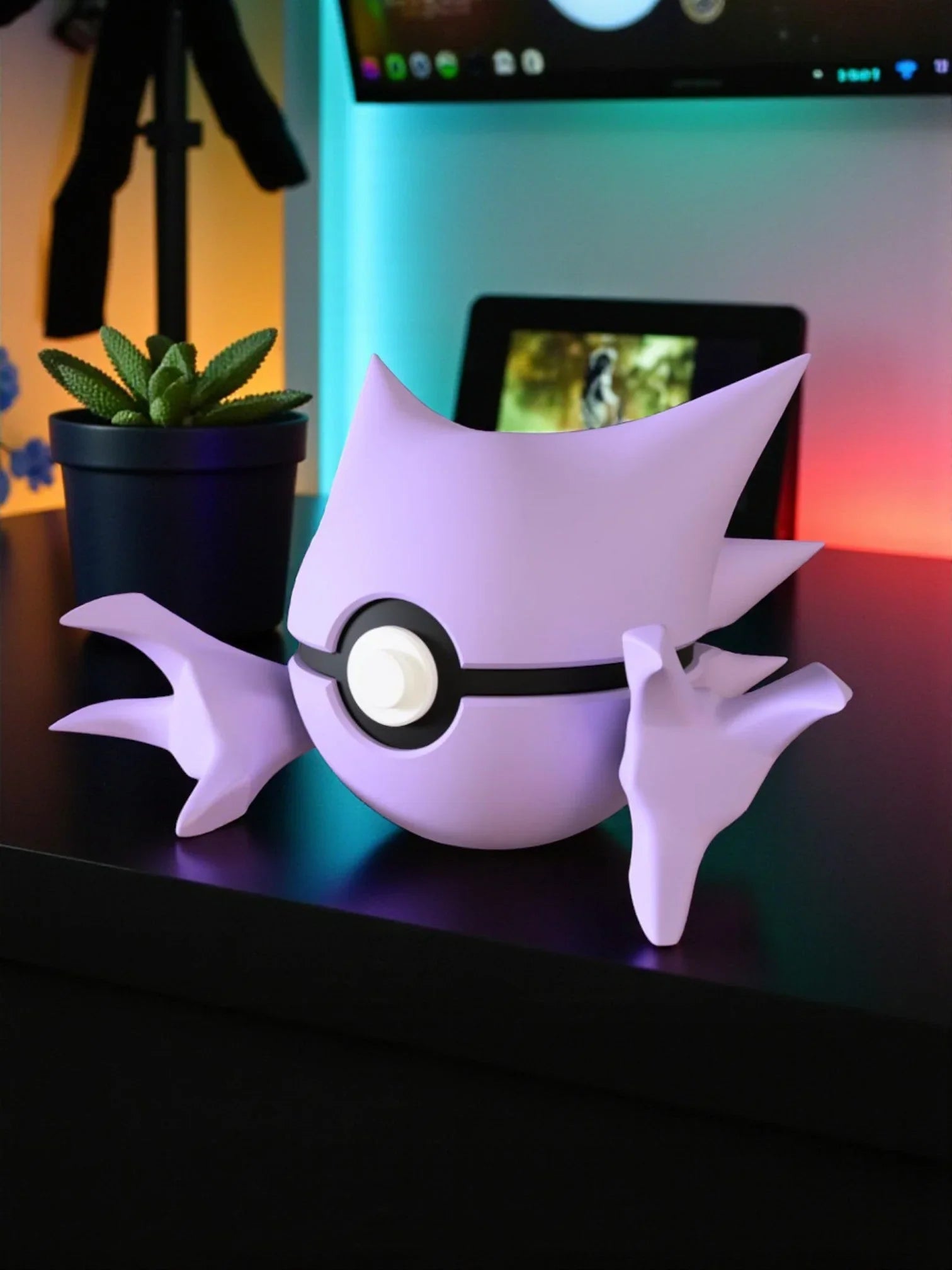 Pokeball decorativa a tema Haunter color lilla su scrivania moderna con pianta grassa