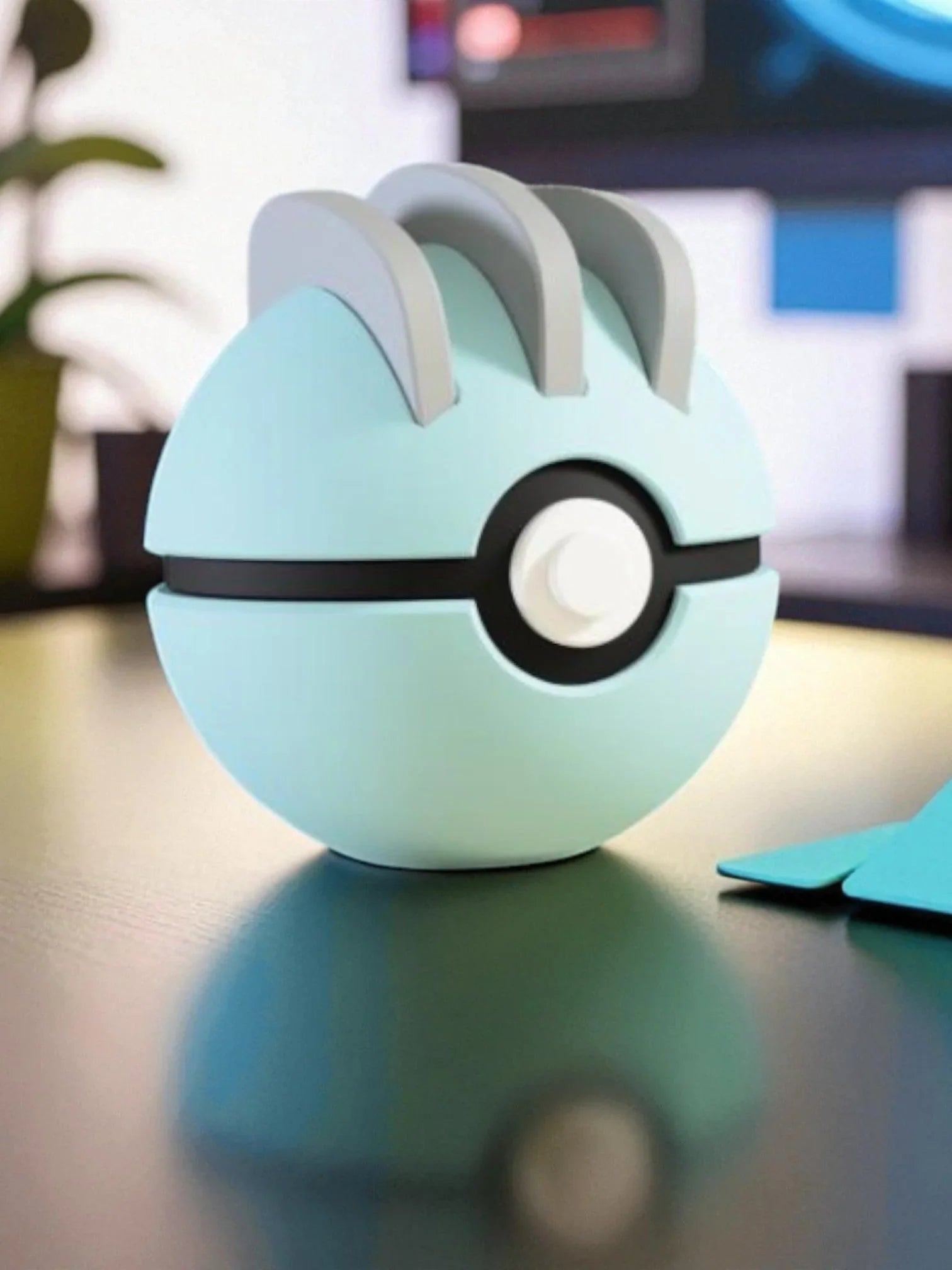 Pokeball azzurra ispirata a Machop con dettagli grigi, esposta su tavolo moderno