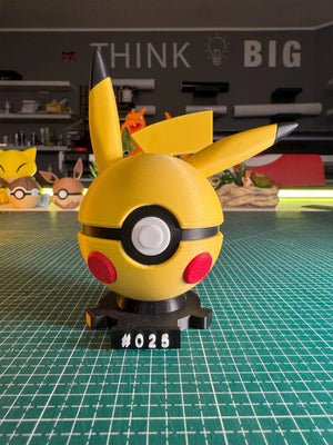 Pokeball ispirata a Pikachu con orecchie grandi, base magnetica numerata #025, su tavolo da taglio.