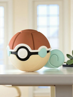 Pokeball decorativa ispirata a Squirtle con coda blu su tavolo, luce naturale.
