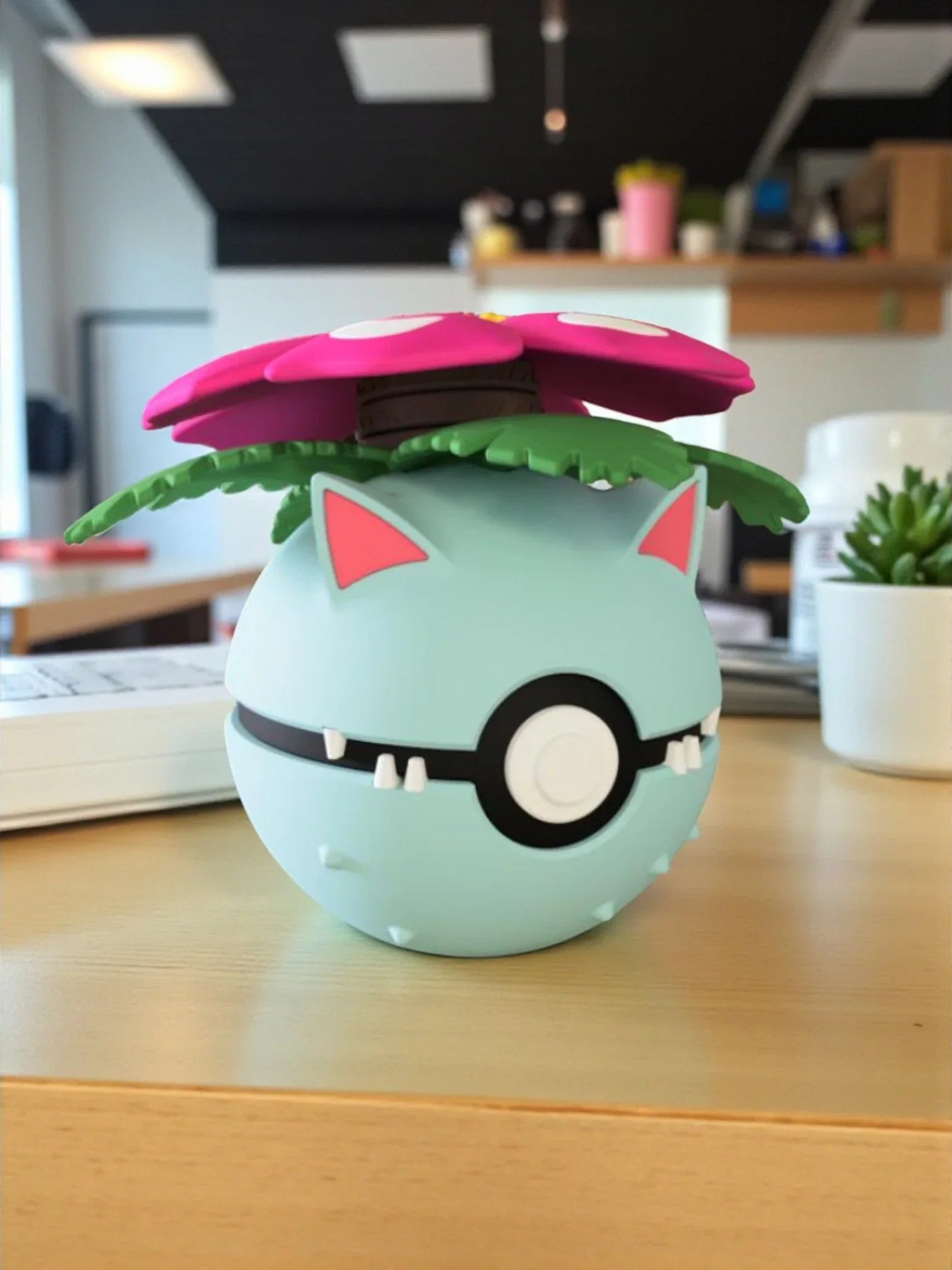 Pokeball ispirata a Venusaur con base magnetica numerata, su un tavolo in ambiente moderno.