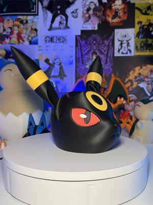 Supporto controller gaming a forma di Umbreon Pokémon su sfondo con poster anime.