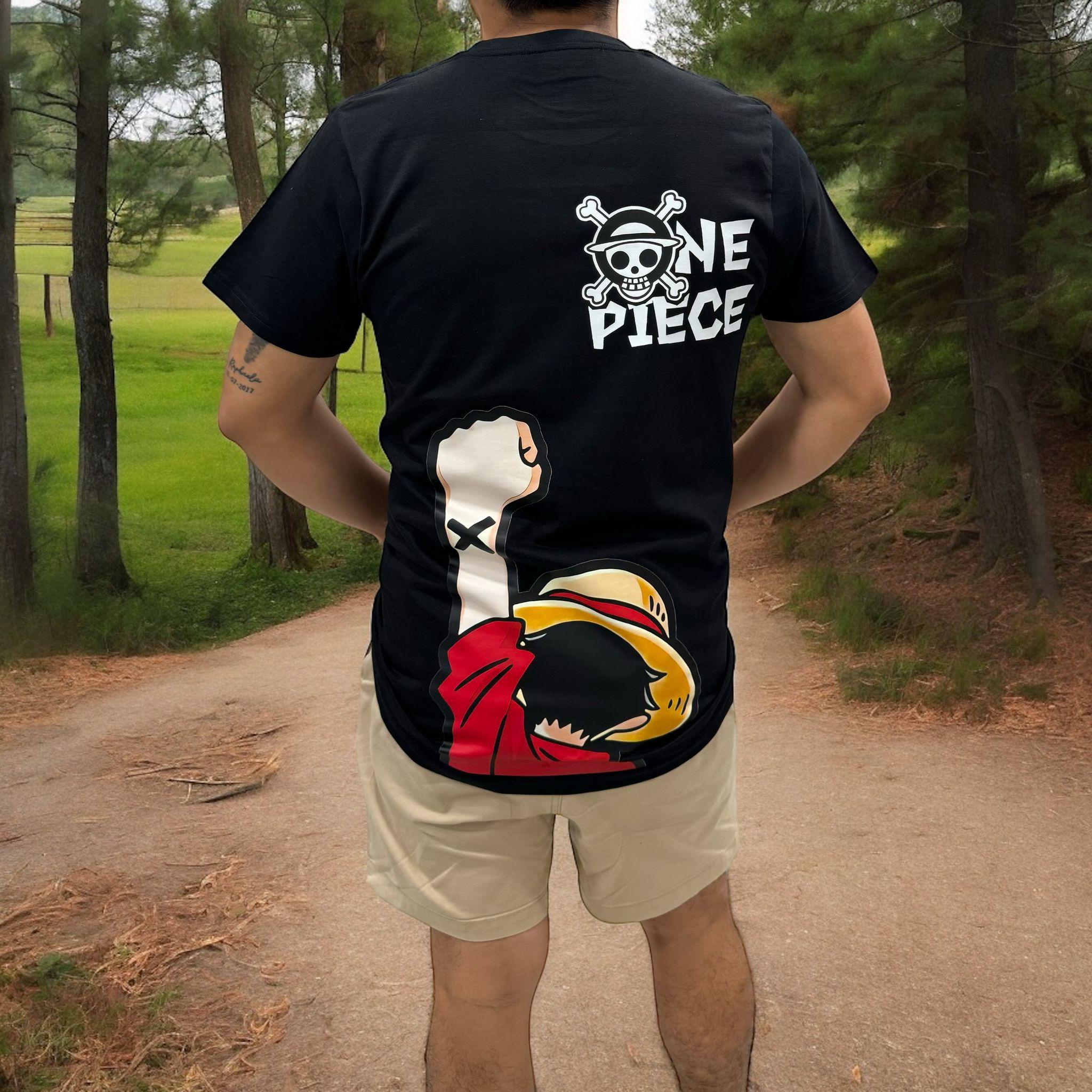 T-shirt nera One Piece con stampa Mugiwara e logo, indossata all’aperto in un bosco.