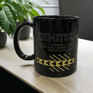 Tazza nera Zenitsu Kimetsu no Yaiba con scritta e design giallo, su tavolo con piante