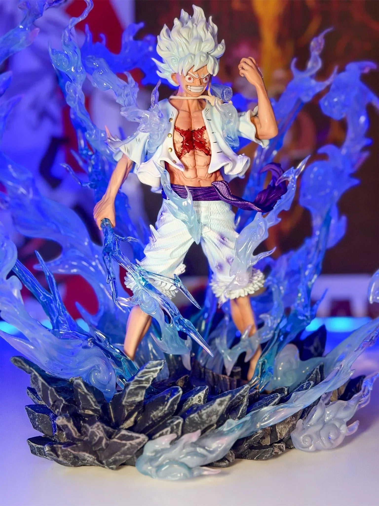 Action figure Monkey D. Luffy Gear 5 One Piece con effetti energia blu, base rocciosa.