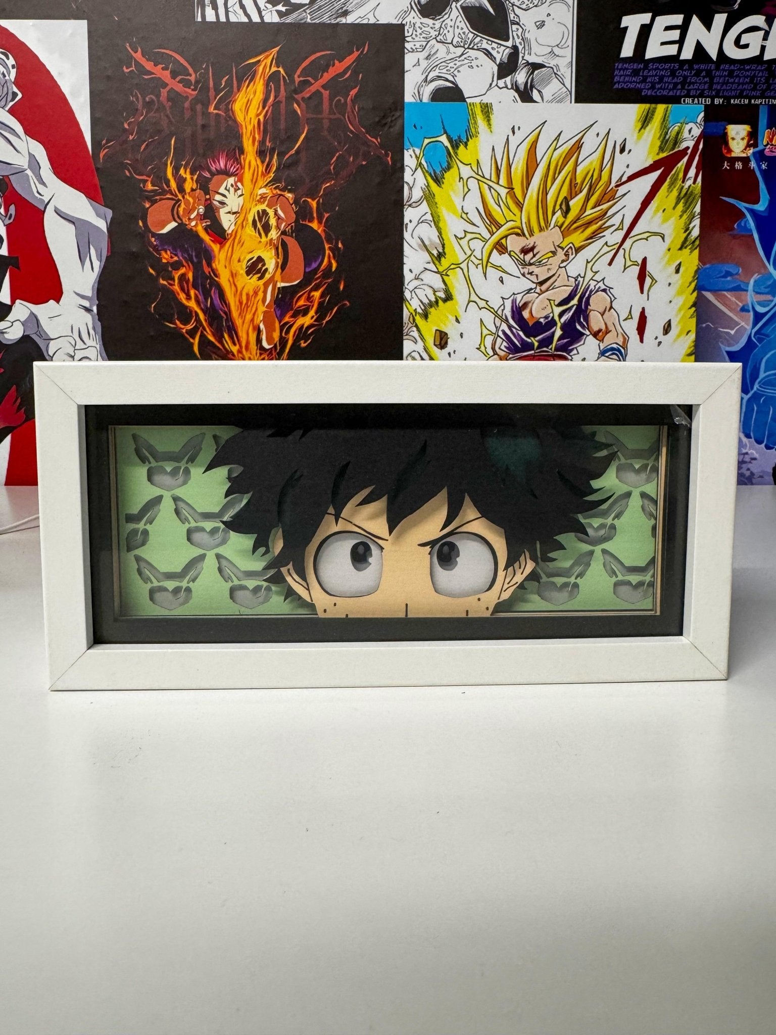 Light box Deku My Hero Academia in cornice bianca, sfondo con poster anime colorati.