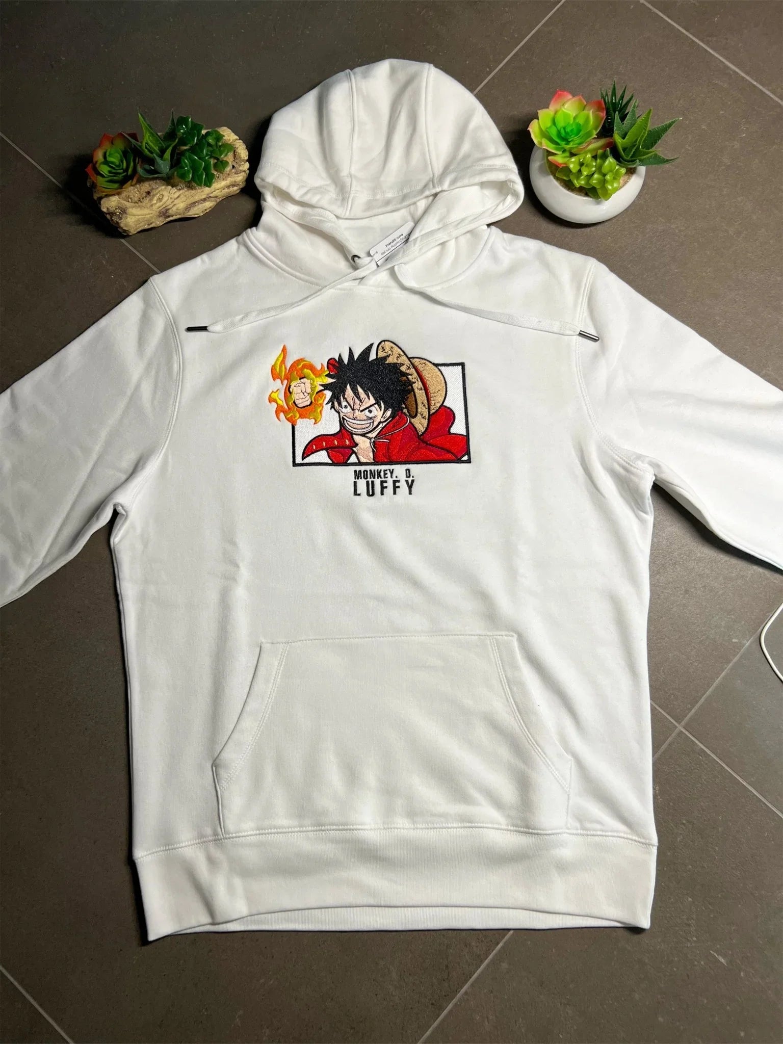 Felpa bianca con ricamo Monkey D. Luffy One Piece, cappuccio e tasca frontale, su sfondo grigio.