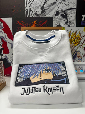 Felpa bianca ricamata Gojo Satoru Jujutsu Kaisen, piegata su sfondo anime, 100% Made in Italy.