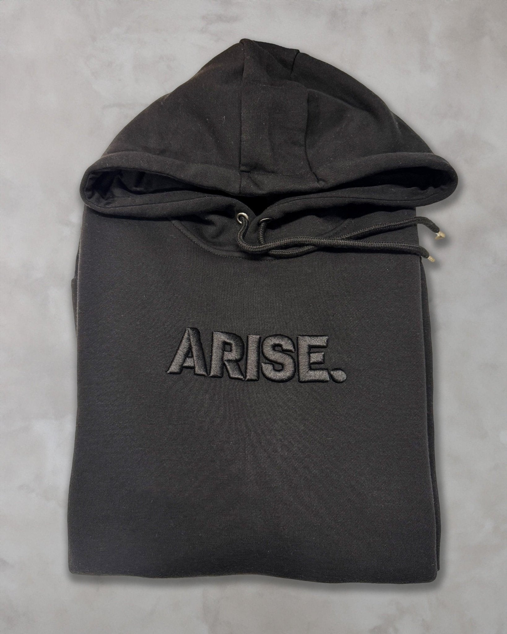 Felpa nera con cappuccio ricamata ARISE, stile anime, piegata su sfondo chiaro