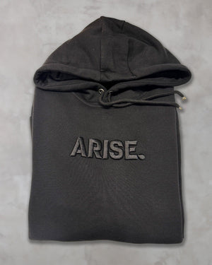 Felpa nera con cappuccio ricamata ARISE, stile anime, piegata su sfondo chiaro