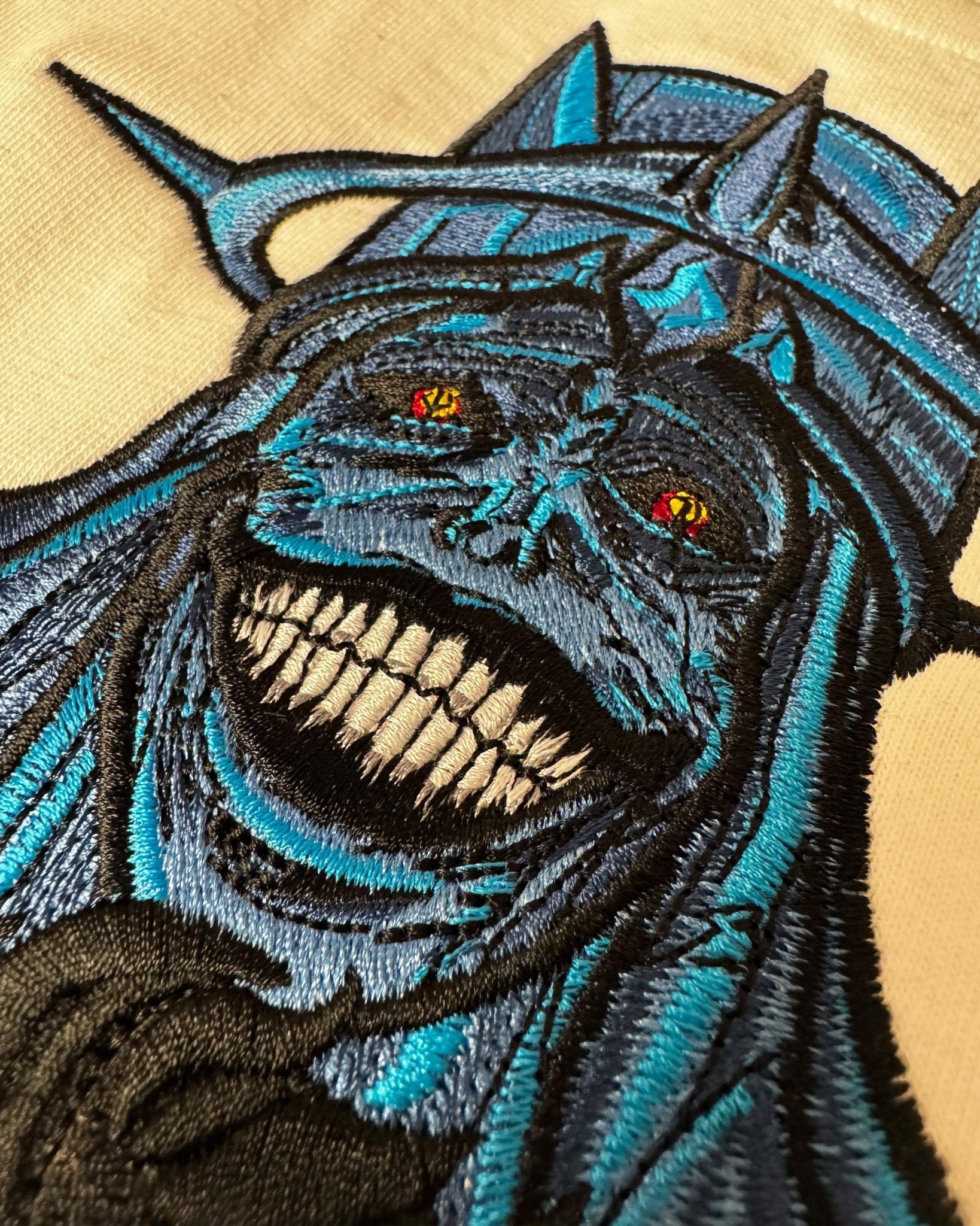Ricamo dettagliato su felpa di personaggio oscuro in stile anime, occhi rossi e sorriso minaccioso.
