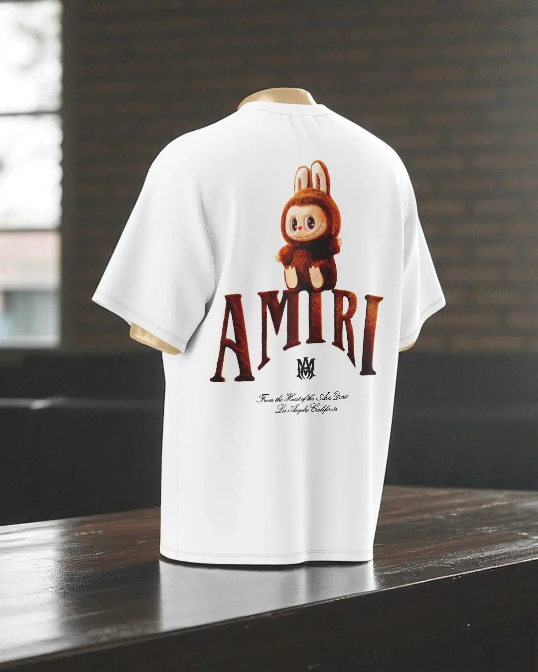 T-shirt oversize bianca con stampa grande di personaggio cartoon marrone e scritta AMIRI sul retro.