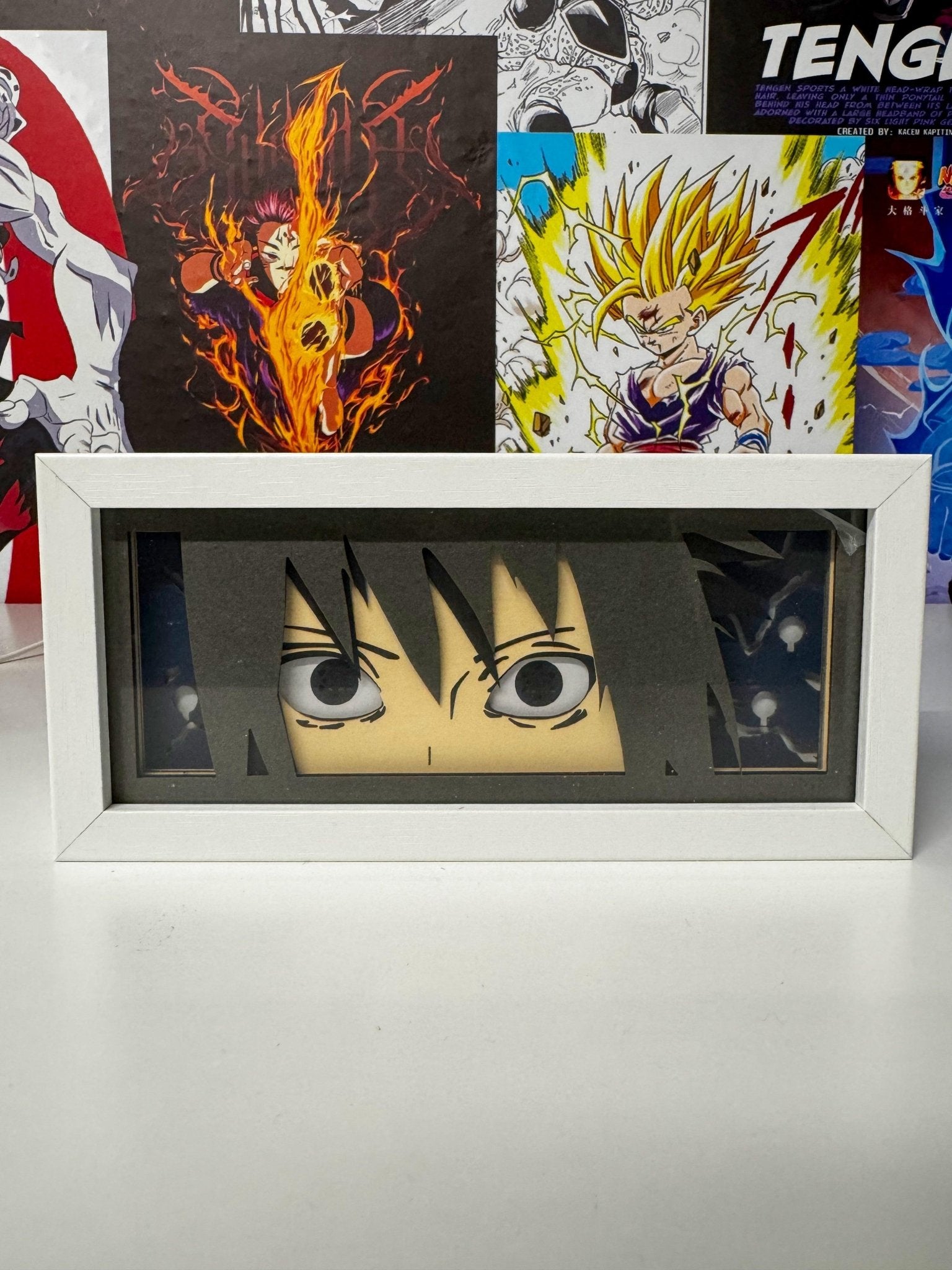 Light box decorativo anime con occhi di Sasuke Sharingan da Naruto in cornice bianca, sfondo manga.