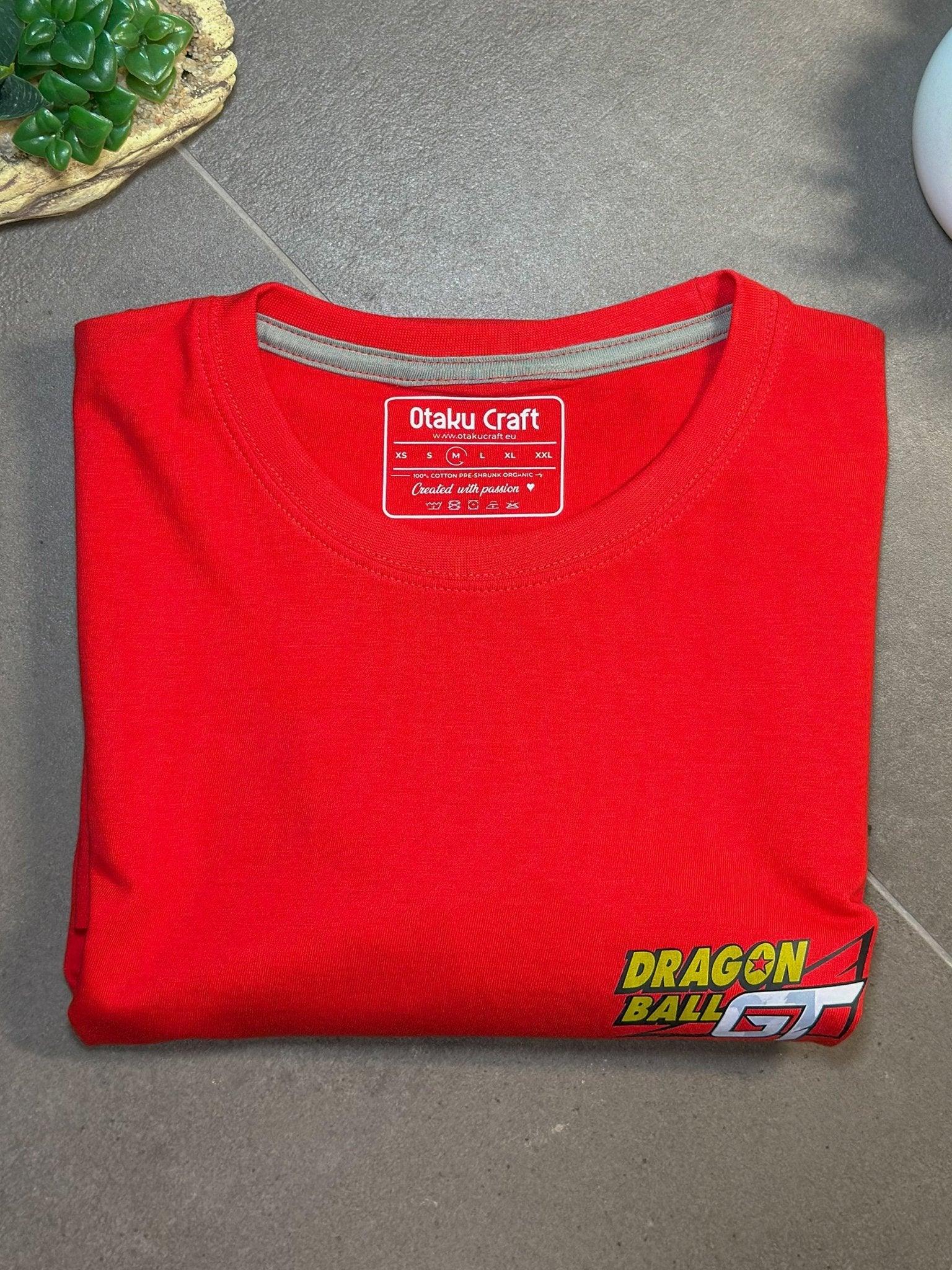Maglietta rossa piegata con logo Dragon Ball GT in basso, stile anime, su sfondo grigio.