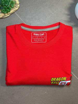 Maglietta rossa piegata con logo Dragon Ball GT in basso, stile anime, su sfondo grigio.