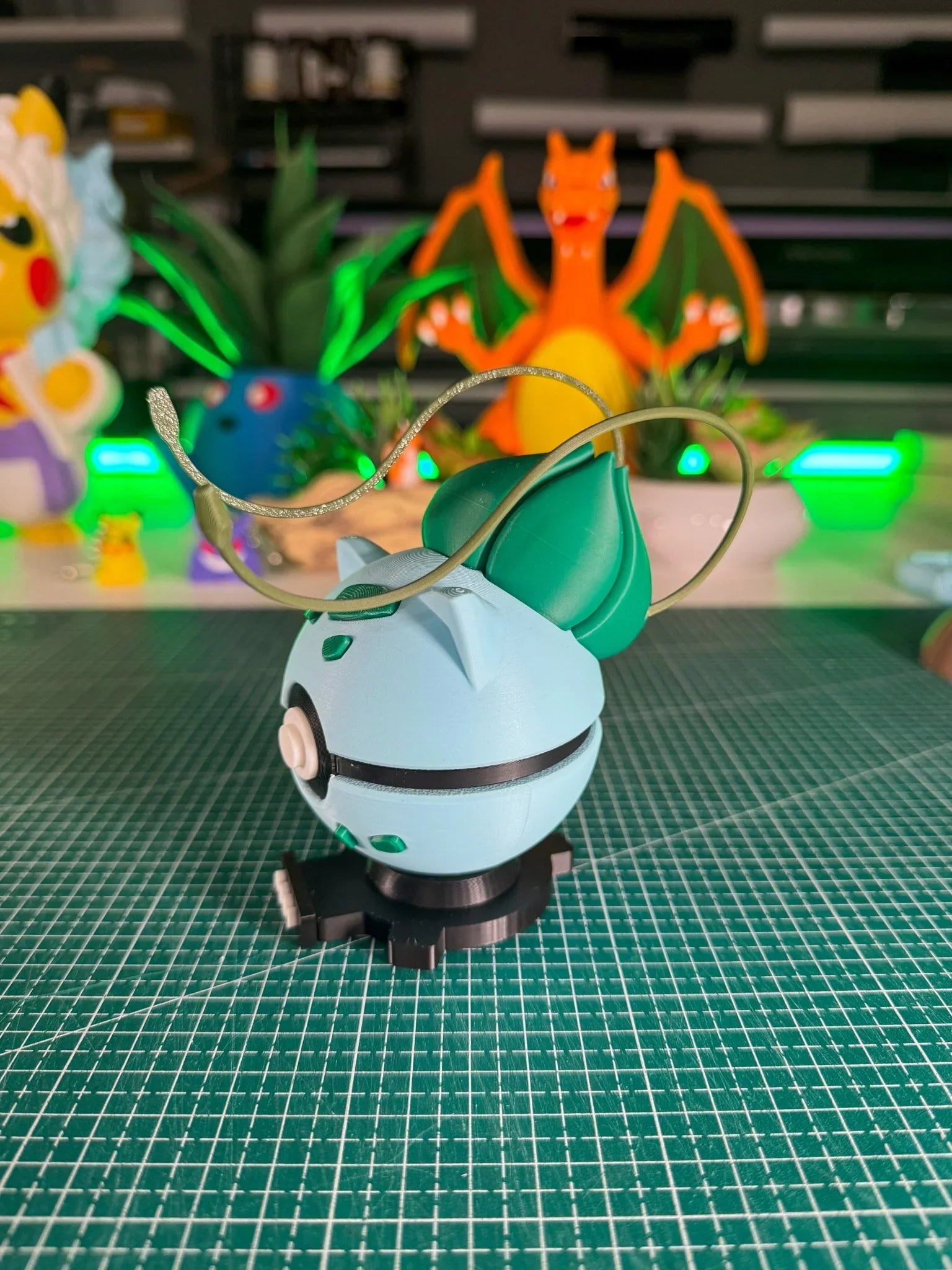 Pokeball Bulbasaur artigianale con base magnetica su tavolo, sfondo figure anime.