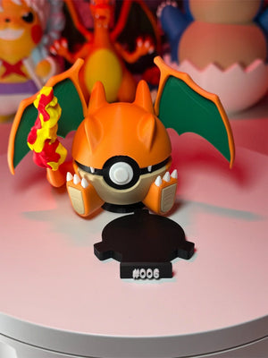 Figura Pokeball ispirata a Charizard con base numerata, ali verdi e dettagli fiamma.