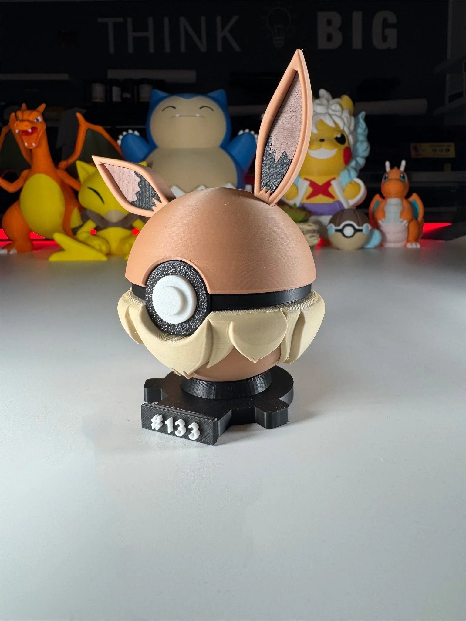 Pokeball ispirata a Eevee con base magnetica numerata, con altri personaggi Pokémon sullo sfondo.