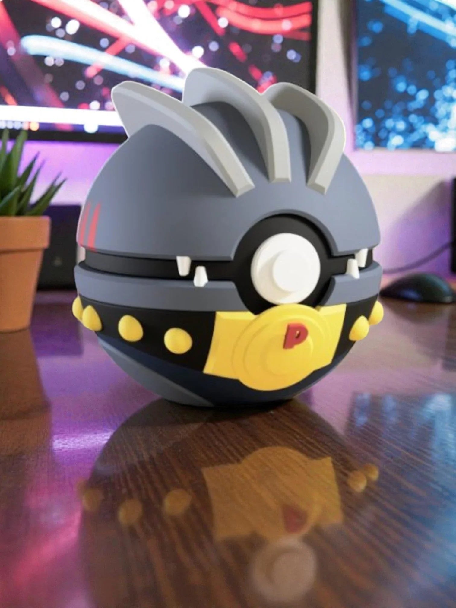 Pokeball personalizzata ispirata a Machoke grigia con dettagli gialli su scrivania, sfondo colorato