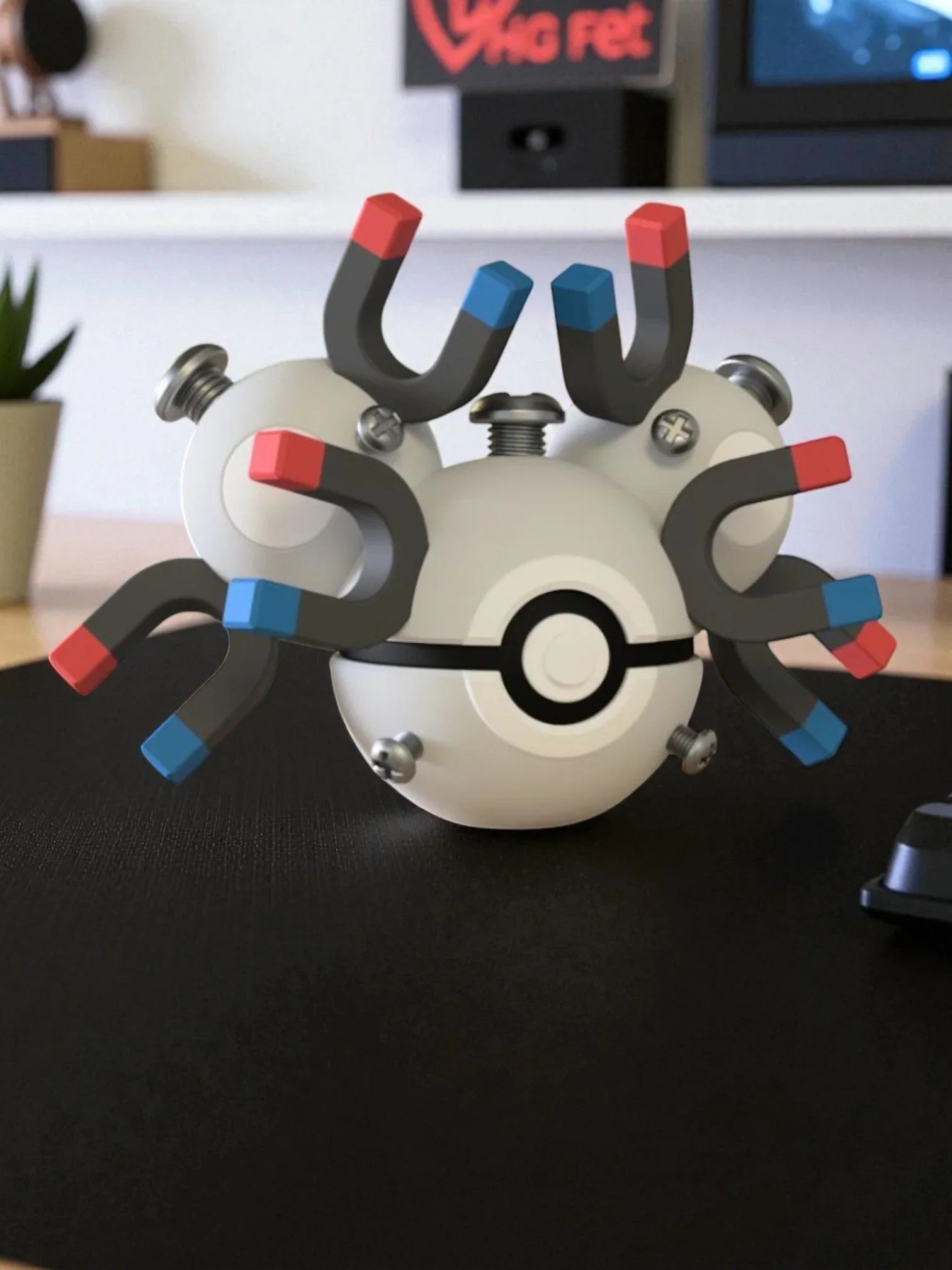 Figura Magneton stile Poké Ball con calamite e viti, su scrivania, dettaglio anime collezionismo.