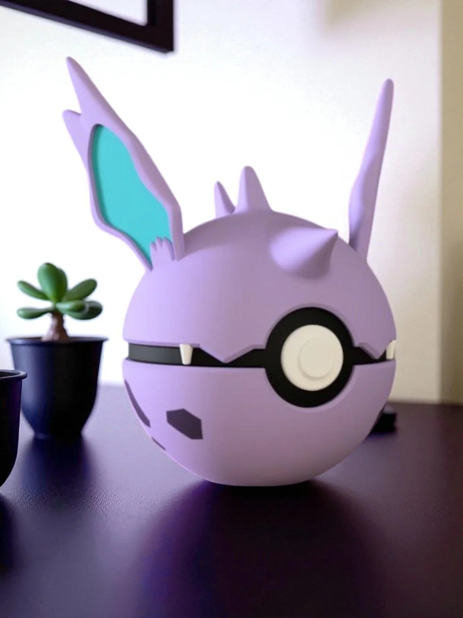Pokeball personalizzata ispirata a Nidorino, viola con dettagli orecchie e zanne, su scrivania.