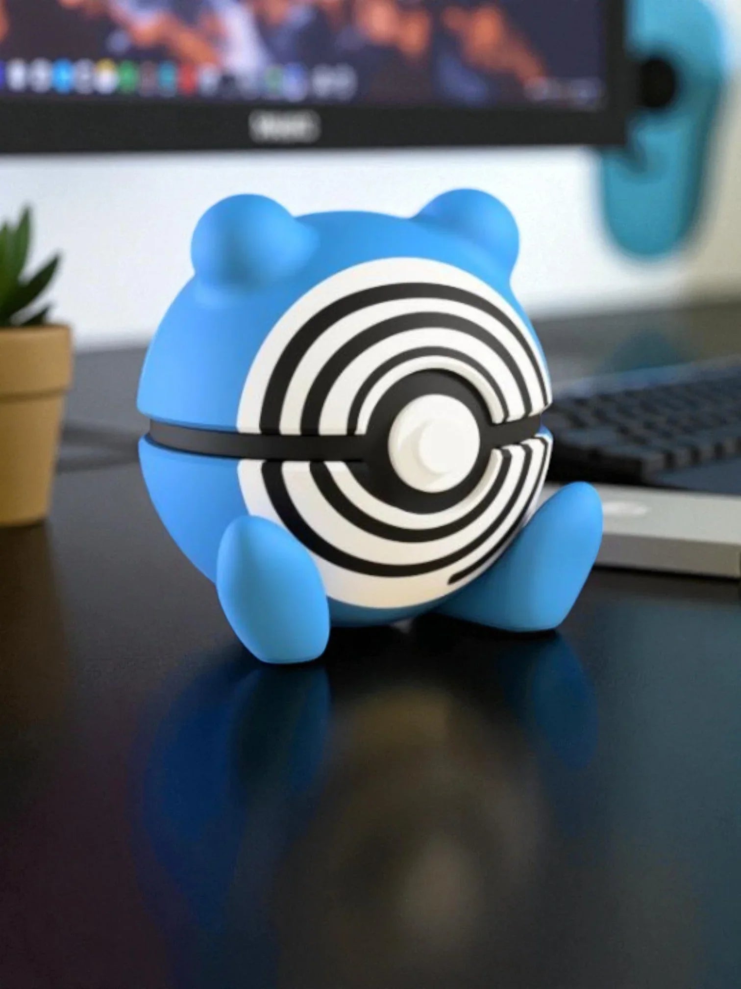 Pokeball Poliwhirl con design blu e dettagli a spirale su scrivania, accessorio da collezione Pokémon.