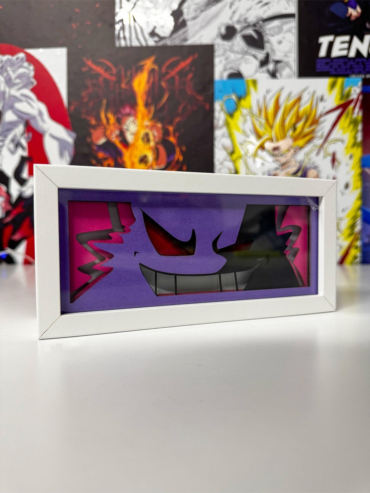 Light box decorativo Gengar Pokémon viola e rosa con cornice bianca, stile anime, su sfondo di poster manga.