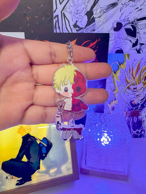Portachiavi anime chibi con personaggio biondo e accessori, sfondo decorato manga.
