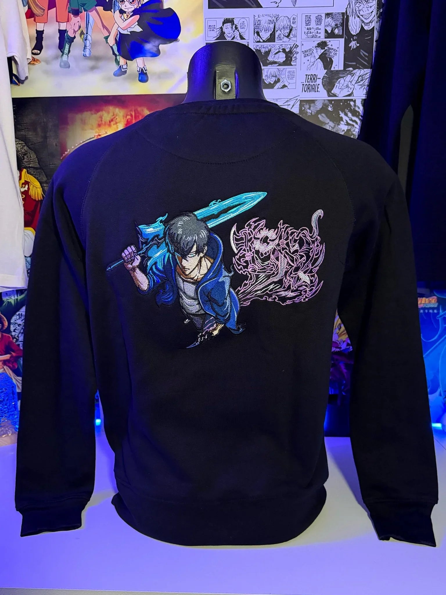 Felpa nera ricamata con personaggio anime che impugna spada blu e figura ombrosa, stile Solo Leveling.