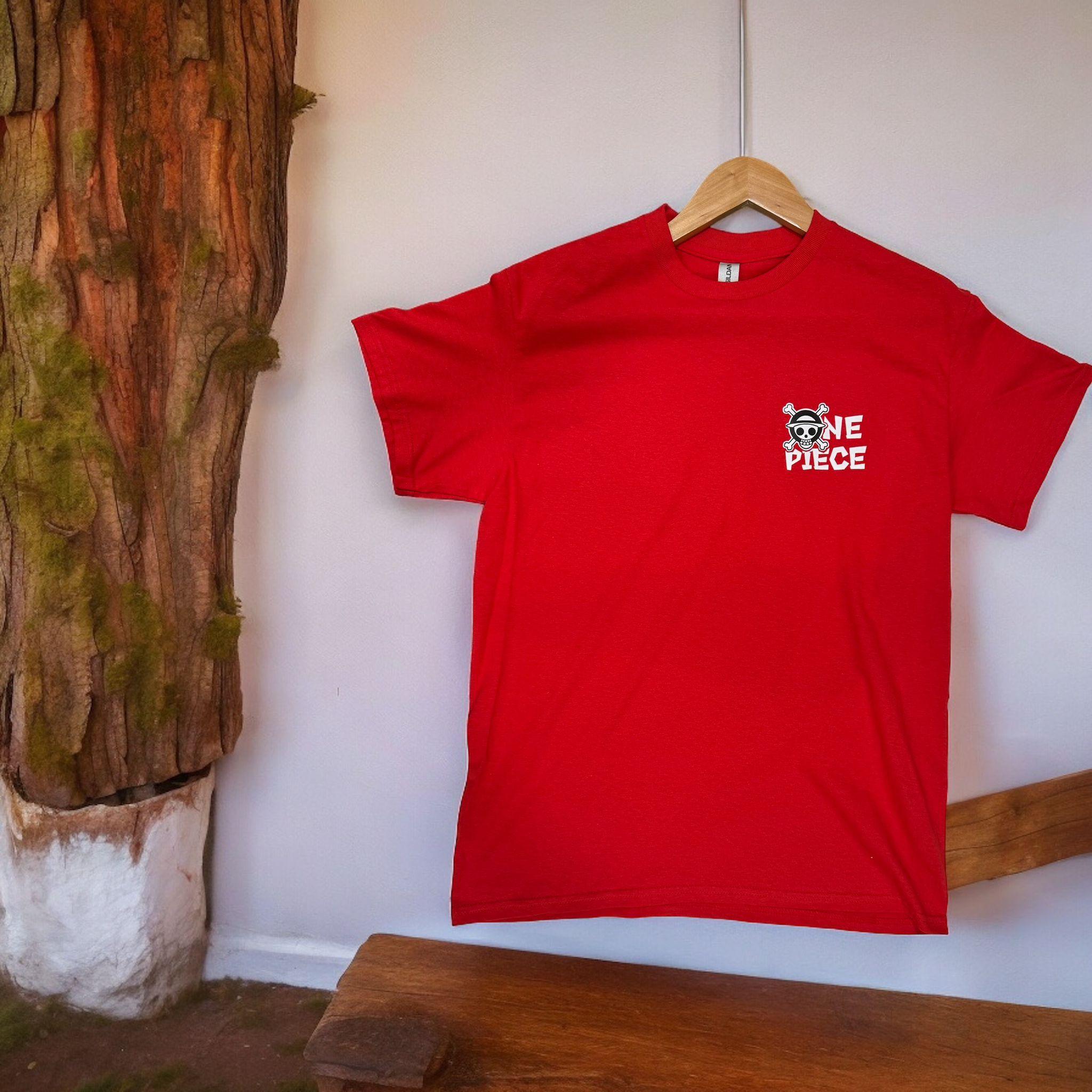 T-shirt rossa con logo One Piece e simbolo Jolly Roger ricamato, appesa su gruccia.