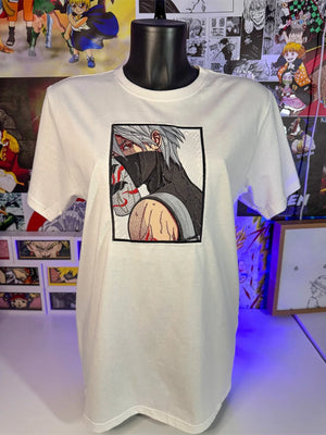 T-shirt bianca anime ricamata con personaggio mascherato, stile manga giapponese, esposta su manichino.