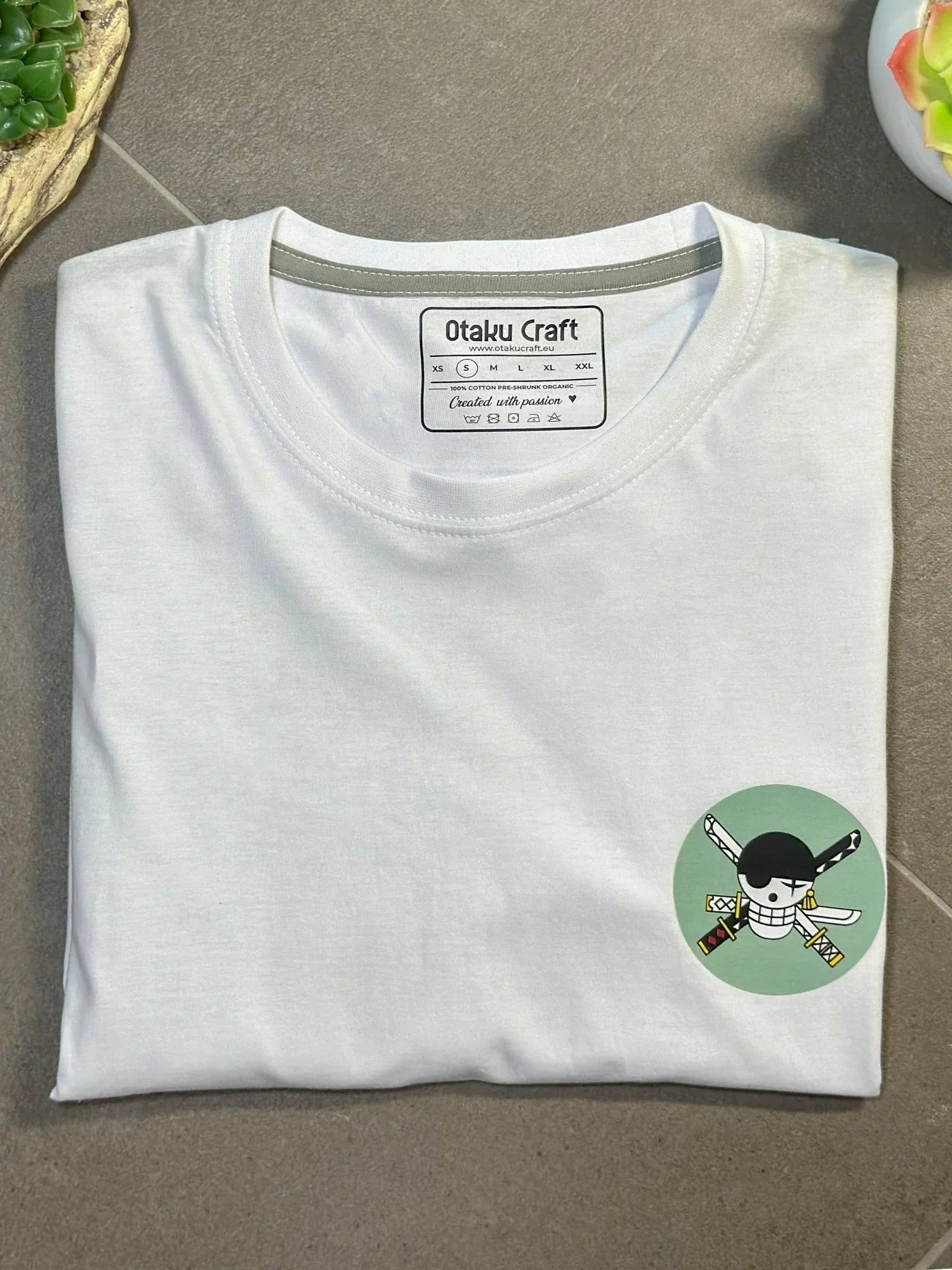 T-shirt bianca con ricamo Zoro Roronoa, logo spade One Piece su fondo verde